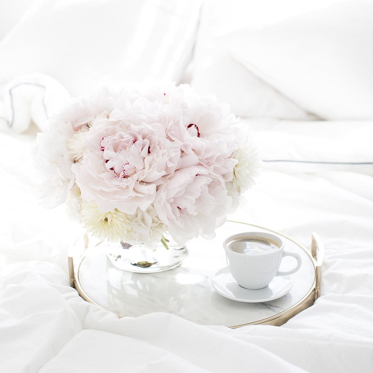 Soft pink and white flower bouquet and coffee cup on a breakfast tray