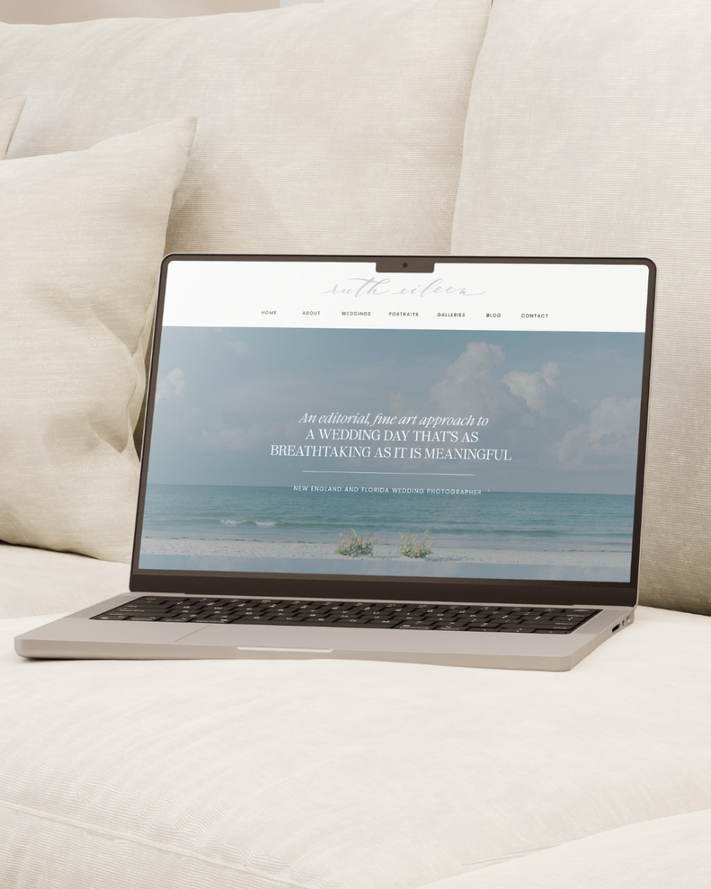 Laptop showing a Showit wedding photography website homepage with an ocean background and fine art design style.