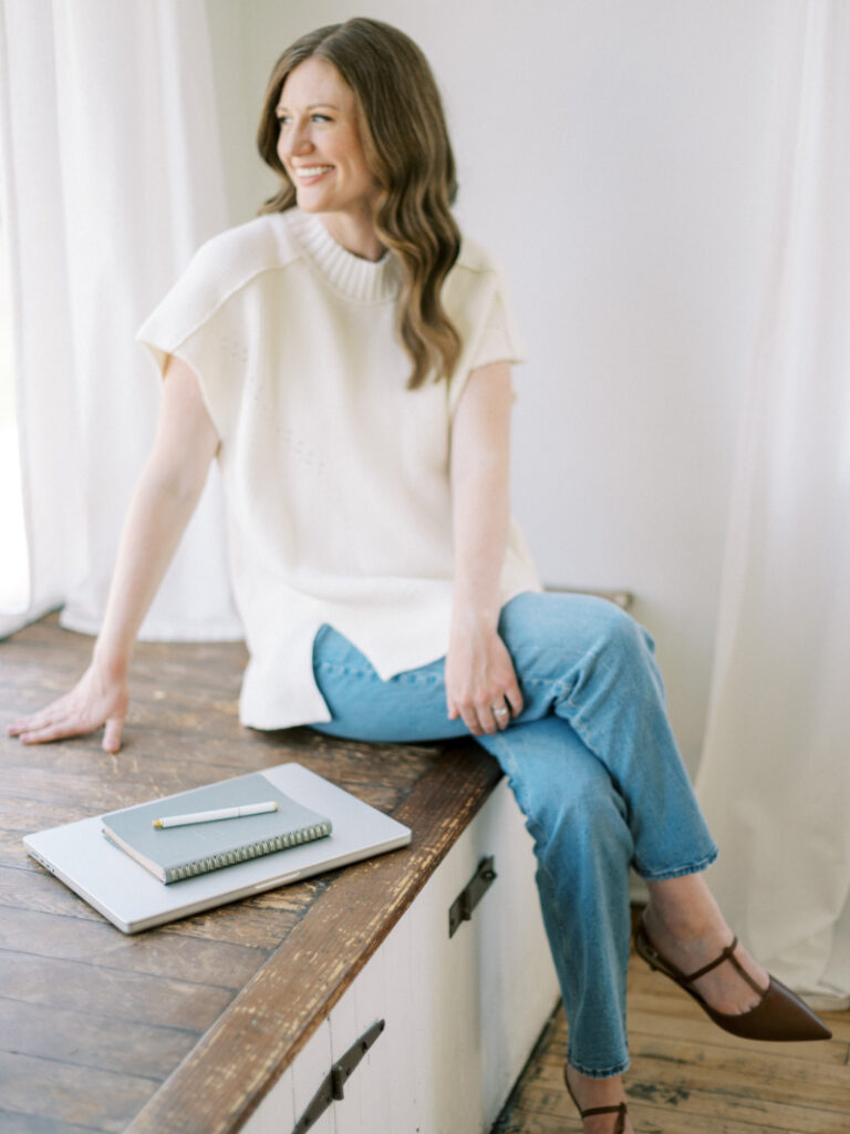 Brand designer seated by window, supporting marketing for wedding planners with refined website strategy.