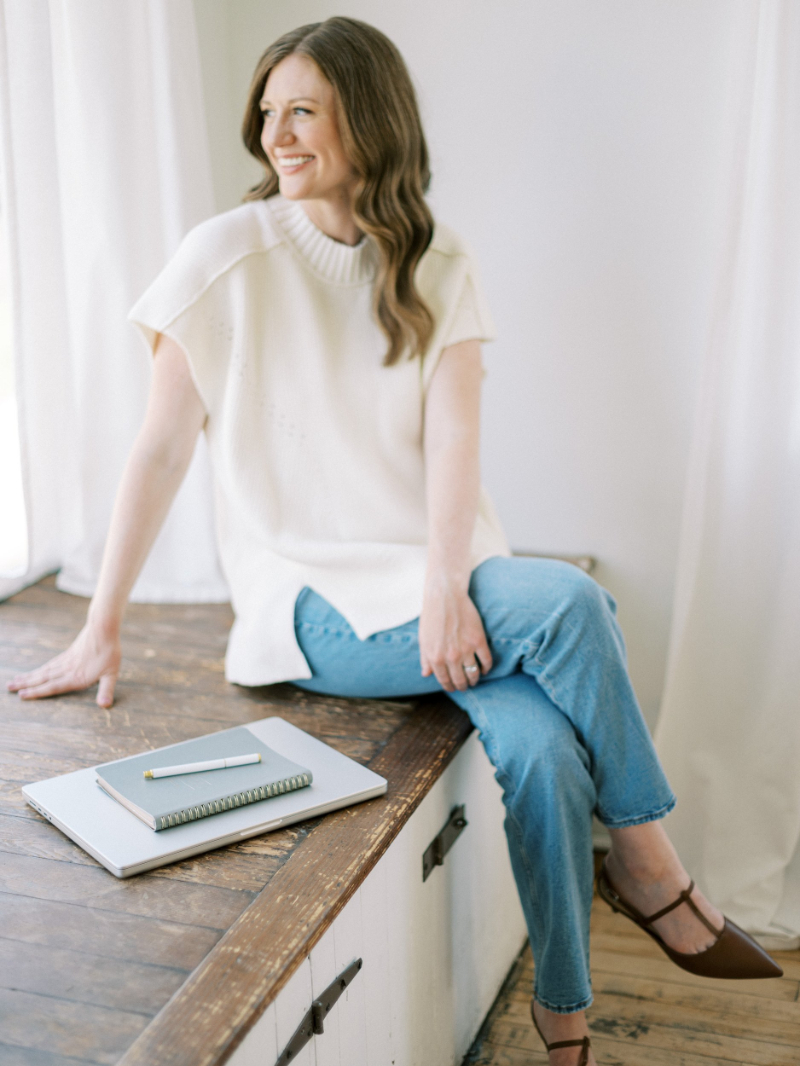 Brand designer seated by window, supporting marketing for wedding planners with refined website strategy.