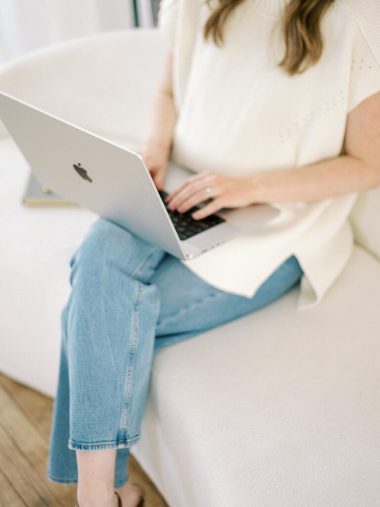 Website mistakes shown through woman working on laptop, clean workspace, and soft, minimal brand aesthetic.